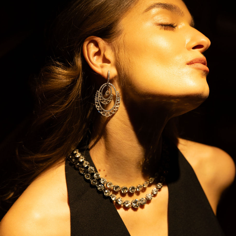 Woman wearing a necklace and Aurelia rose-cut diamond drop earrings with a warm glow