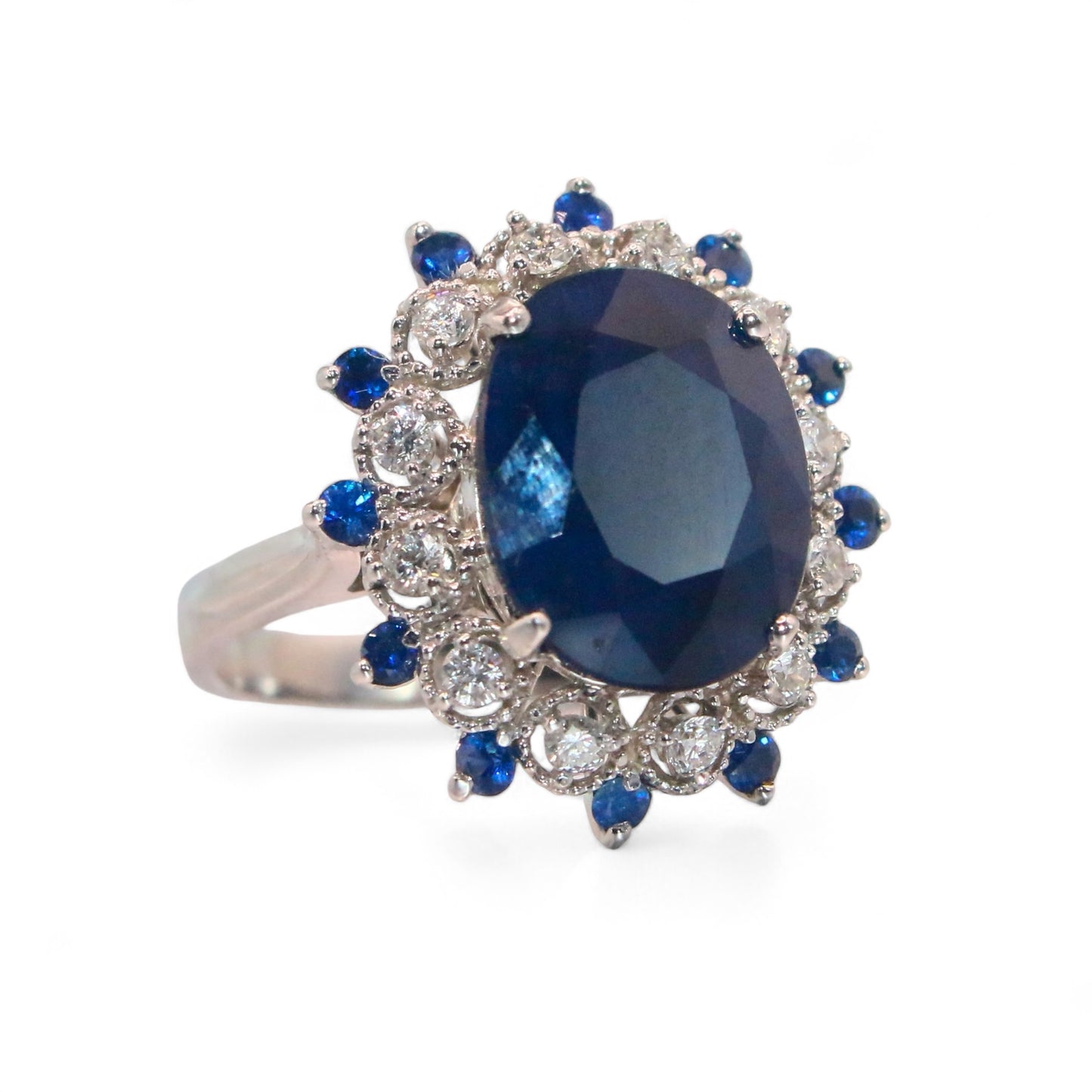 Laurenti Diana Ring featuring an oval blue sapphire surrounded by diamonds and sapphires in 14K white gold.