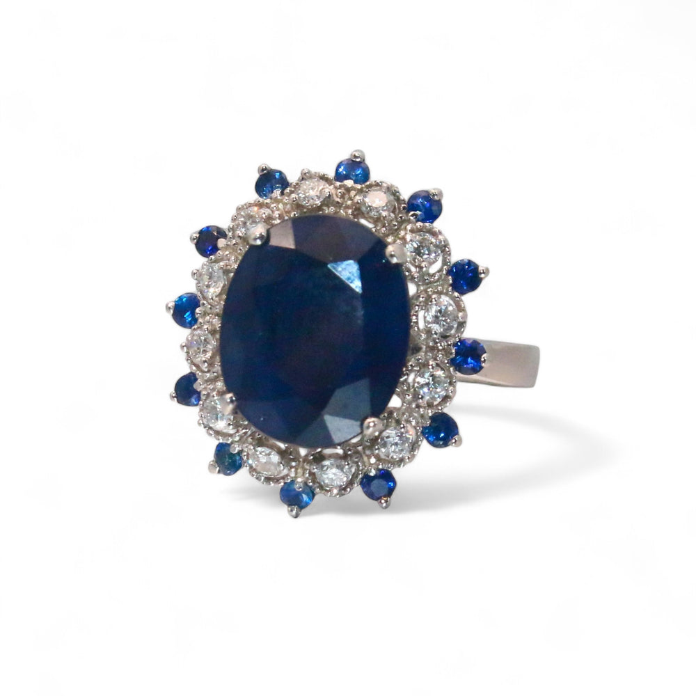 
                  
                    Laurenti Diana Ring featuring an oval blue sapphire surrounded by diamonds and sapphires in 14K white gold.
                  
                