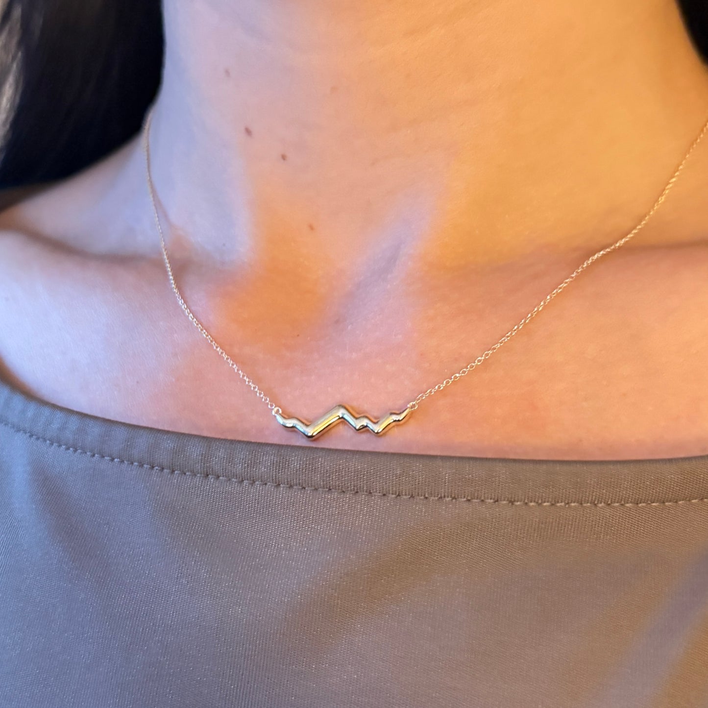 Gold Jackson Hole necklace on a person wearing a beige top