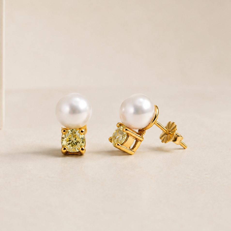 Pair of pearl earrings with gold and gemstone accents on a beige background