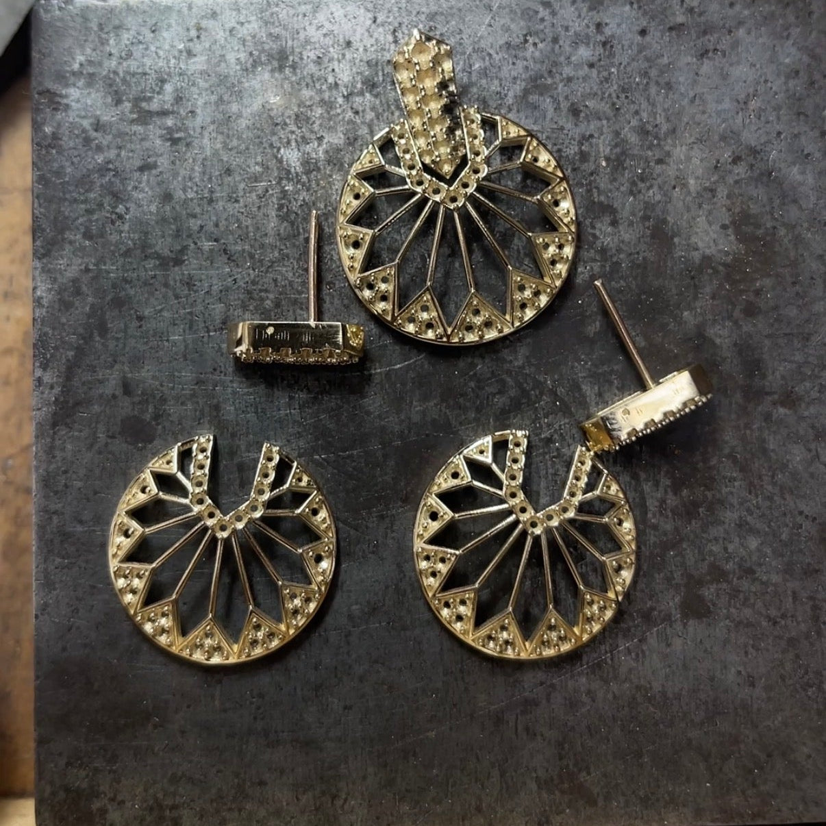 Gold earrings on a dark stone surface