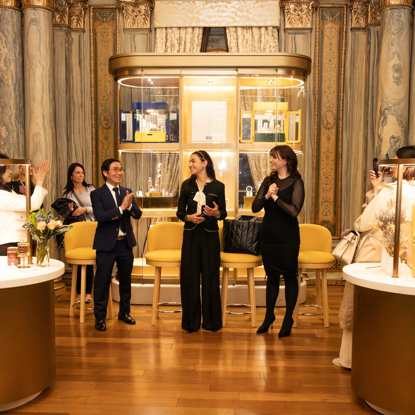 People in a formal setting with chairs and tables, possibly at an event or meeting.