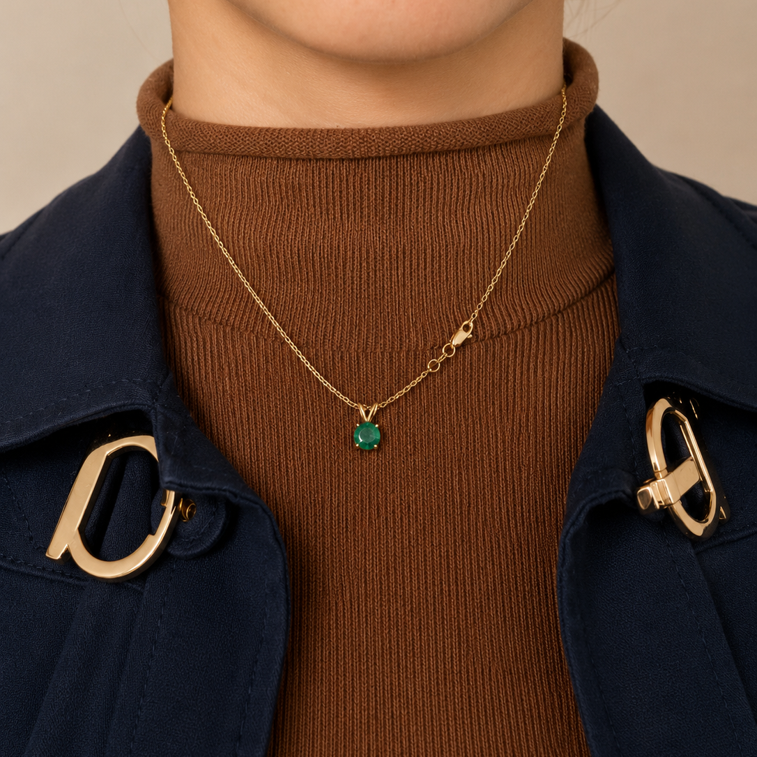 Model wearing Laurenti's natural Colombian emerald solitaire pendant necklace in 14K yellow gold.