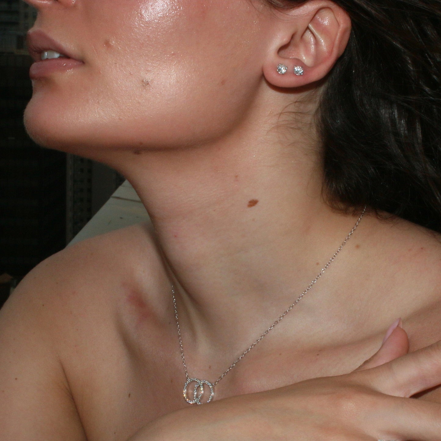 Woman wearing 1.00ct round diamond stud earrings in 14K white gold, styled for everyday elegance
